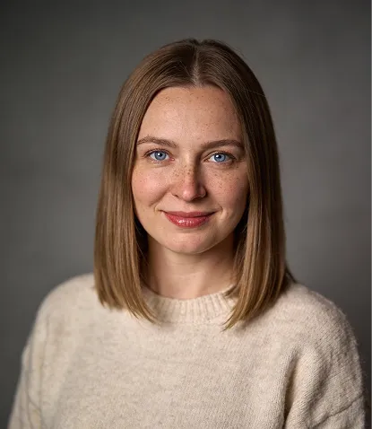 Portrait of Claire Bennett, Project Manager — young woman with light brown hair and freckles in a cream sweater.